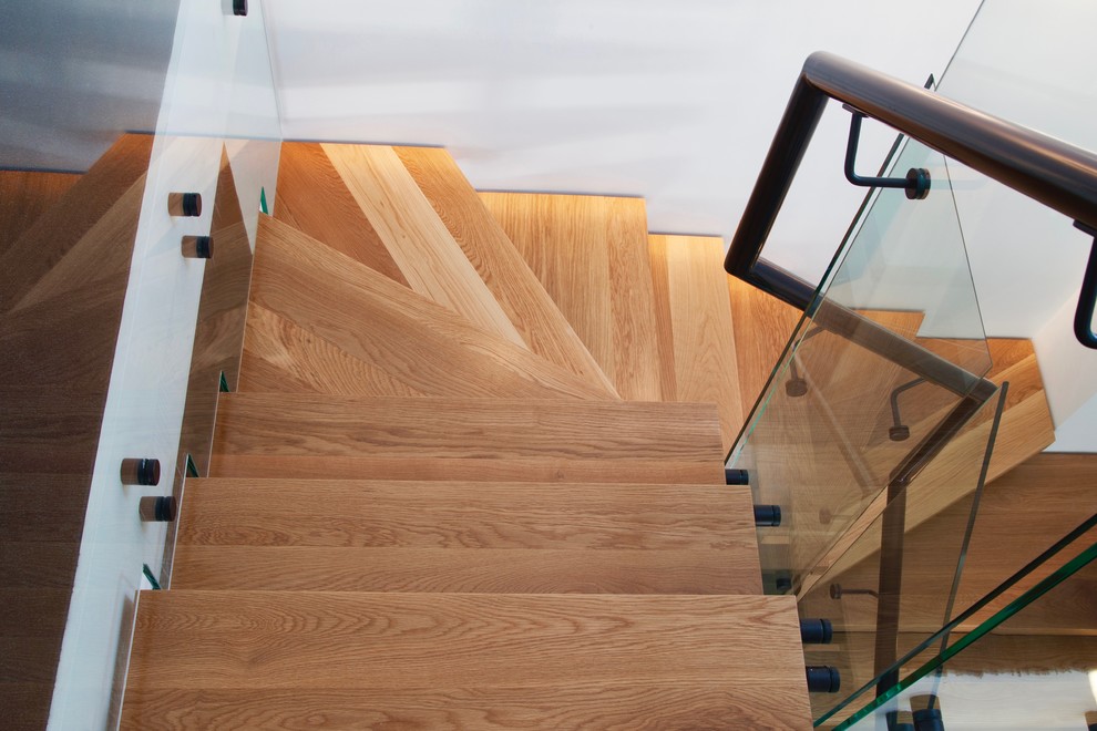 Ejemplo de escalera en L actual con escalones de madera y barandilla de metal