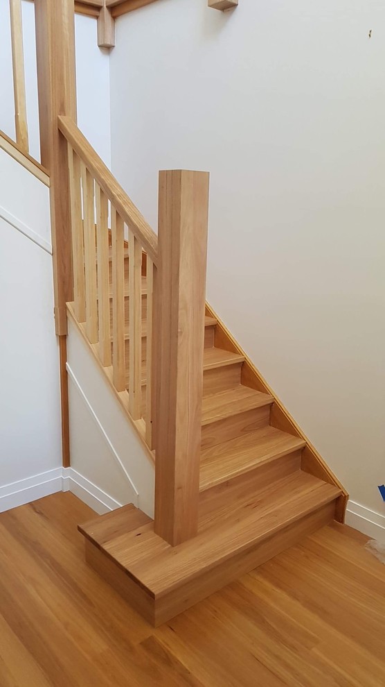 Modelo de escalera curva actual con escalones de madera, contrahuellas de madera y barandilla de madera