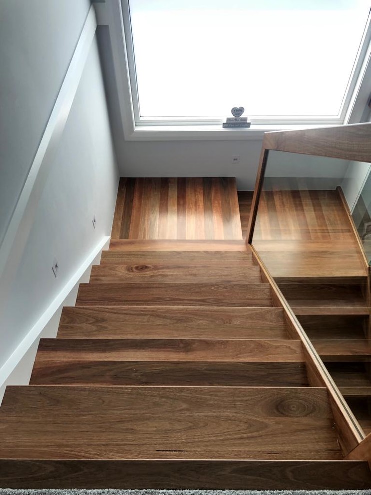 Imagen de escalera en L actual con escalones de madera, contrahuellas de madera y barandilla de madera
