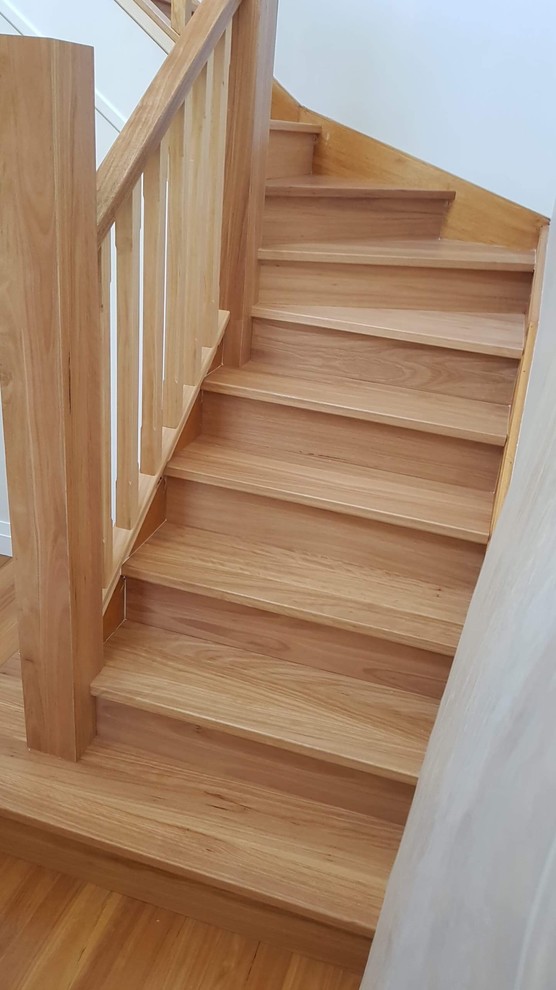 Aménagement d'un escalier courbe contemporain avec des marches en bois, des contremarches en bois et un garde-corps en bois.