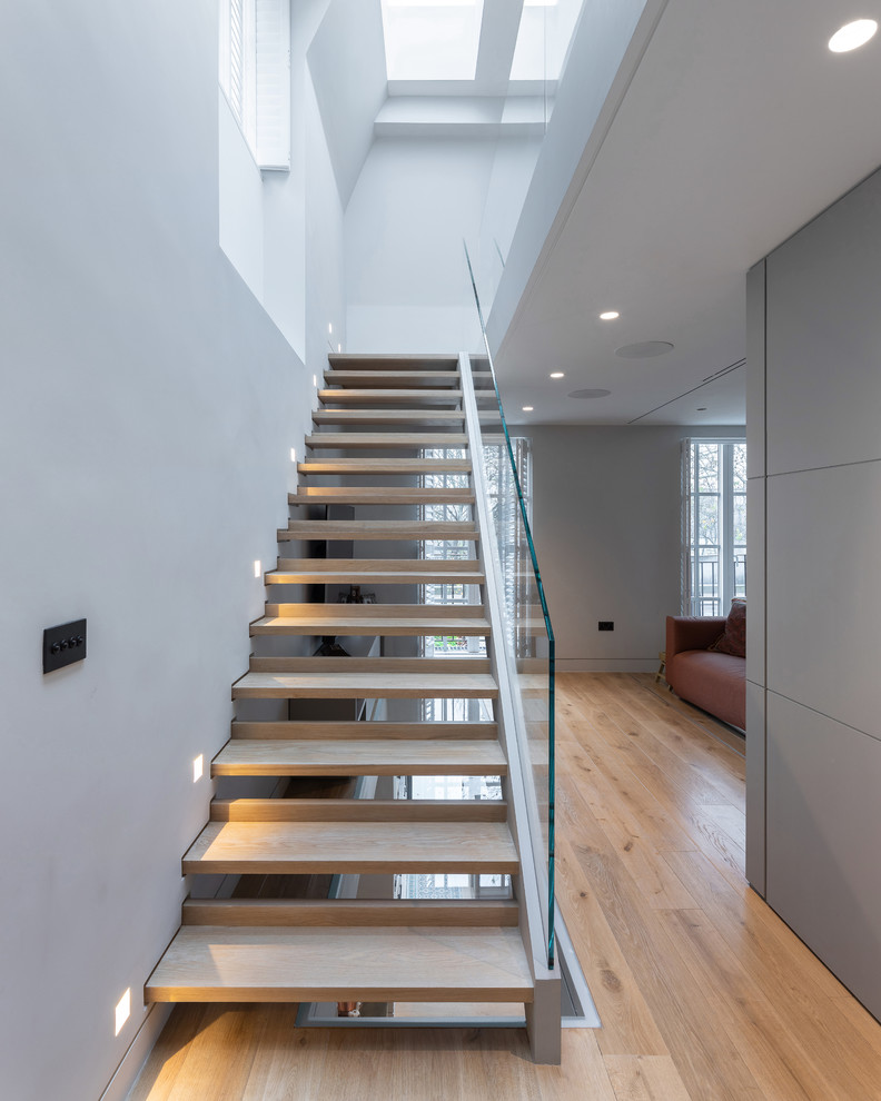 Imagen de escalera recta contemporánea sin contrahuella con escalones de madera y barandilla de vidrio