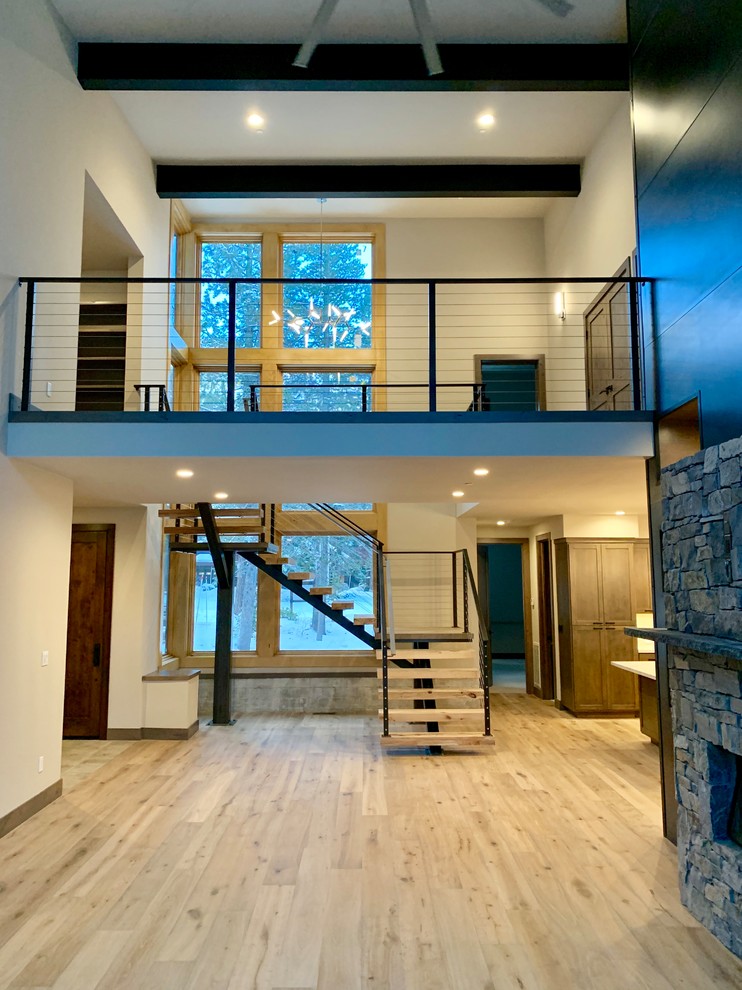 Cette image montre un escalier flottant minimaliste avec des contremarches en bois et un garde-corps en métal.