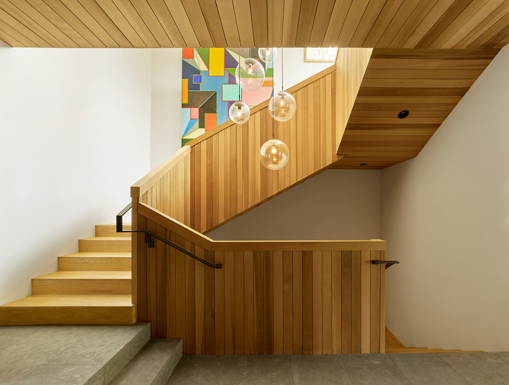 Cette image montre un escalier design en U avec des marches en bois, des contremarches en bois, un garde-corps en bois et palier.