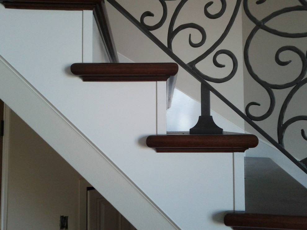 Réalisation d'un très grand escalier peint courbe tradition avec des marches en bois.