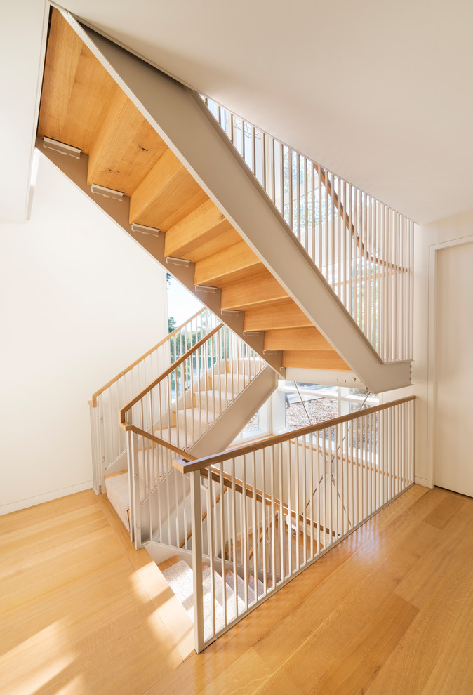 Inspiration pour un grand escalier design en U avec des marches en bois, des contremarches en bois et un garde-corps en métal.