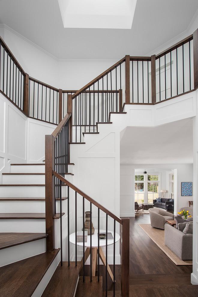 Cette image montre un grand escalier peint courbe traditionnel avec des marches en bois et un garde-corps en matériaux mixtes.