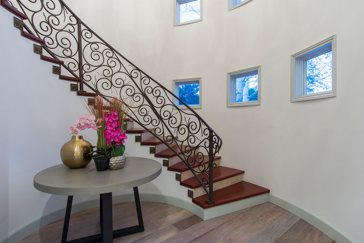 Imagen de escalera curva contemporánea de tamaño medio con escalones de madera, contrahuellas con baldosas y/o azulejos y barandilla de metal