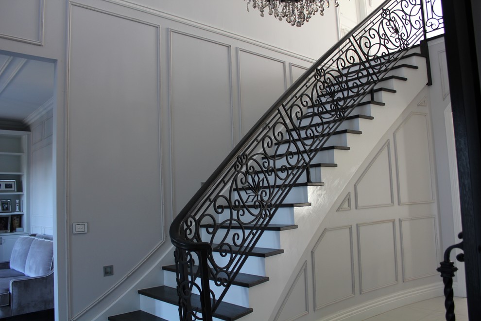 Diseño de escalera curva clásica grande con escalones de madera y contrahuellas de madera pintada