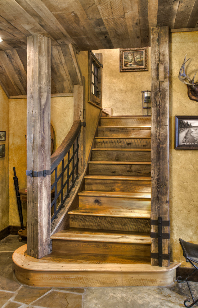 Imagen de escalera curva rural grande con escalones de madera, contrahuellas de madera y barandilla de varios materiales