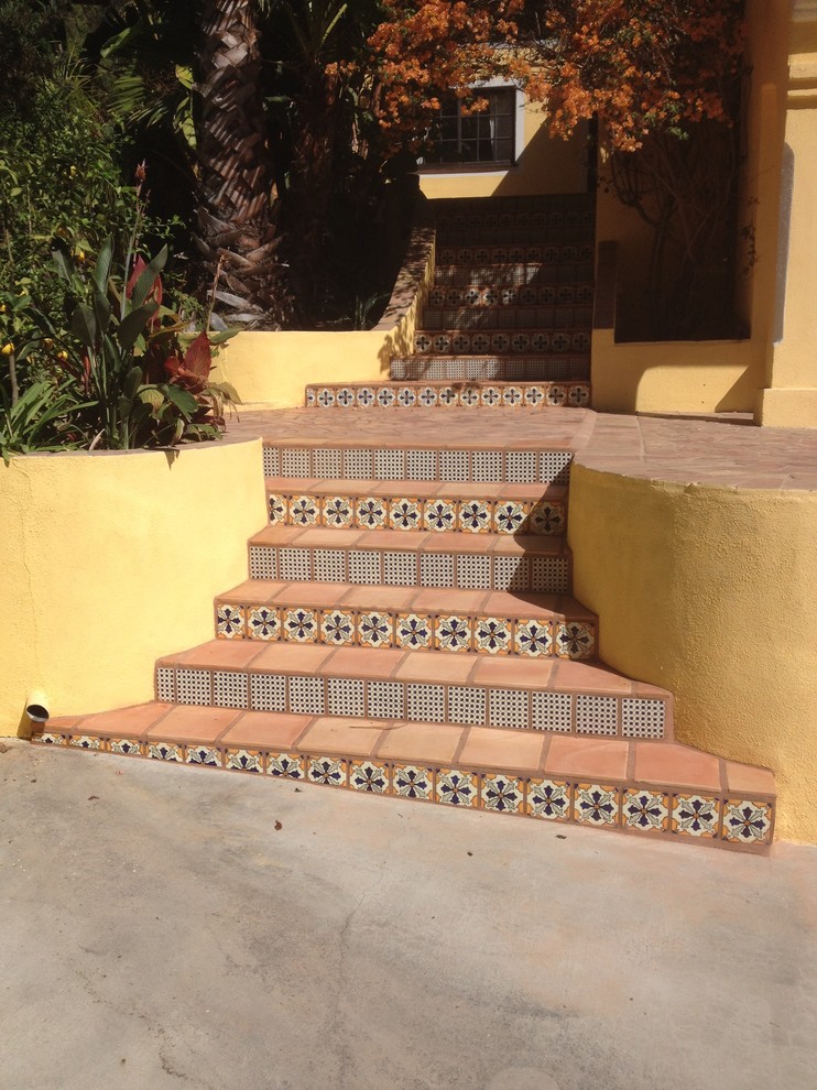 Aménagement d'un escalier méditerranéen avec des marches en terre cuite et des contremarches carrelées.
