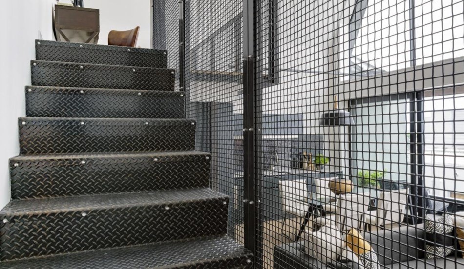 Imagen de escalera recta urbana con escalones de metal, contrahuellas de metal y barandilla de metal