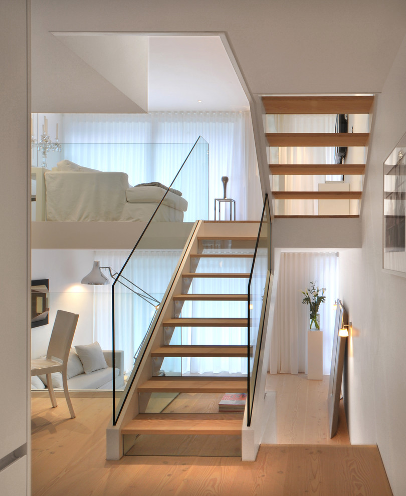 Medium sized scandi wood u-shaped staircase in London with glass risers and feature lighting.