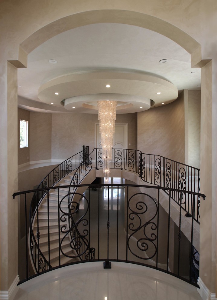 На фото: большая изогнутая лестница в стиле неоклассика (современная классика) с ступенями из плитки и подступенками из плитки