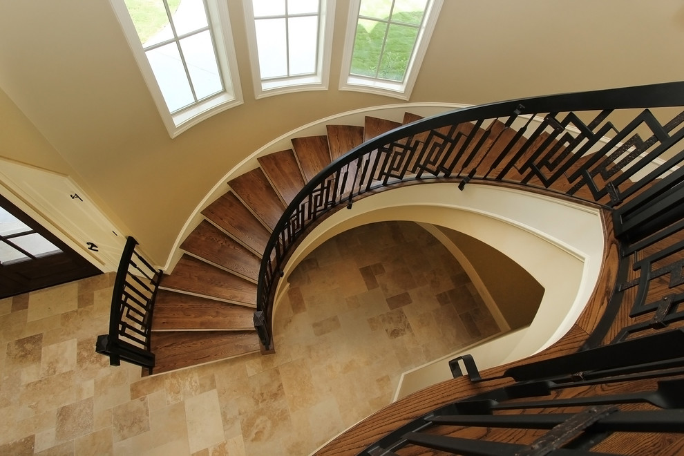 Ejemplo de escalera curva clásica renovada extra grande con escalones de madera y contrahuellas con baldosas y/o azulejos