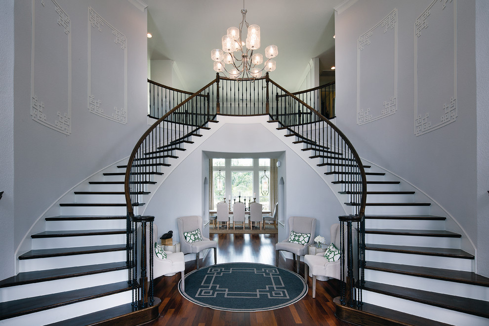 Стильный дизайн: изогнутая лестница в стиле неоклассика (современная классика) с деревянными ступенями и крашенными деревянными подступенками - последний тренд