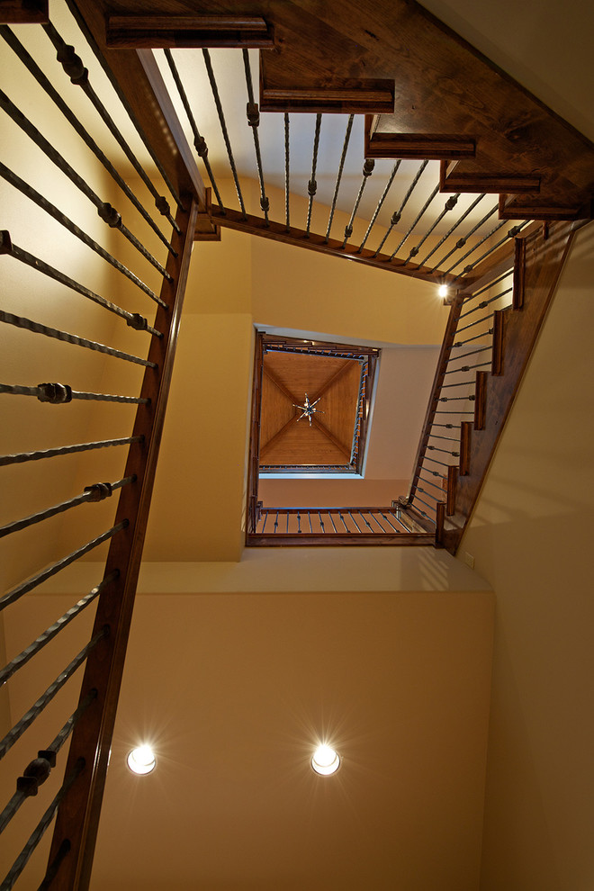 Cette image montre un grand escalier hélicoïdal chalet avec des marches en bois, un garde-corps en métal et éclairage.