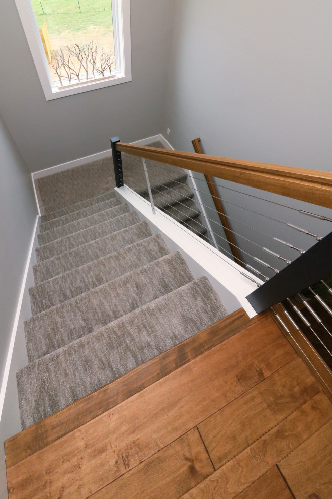 На фото: большая изогнутая лестница в классическом стиле с ступенями с ковровым покрытием, ковровыми подступенками и металлическими перилами