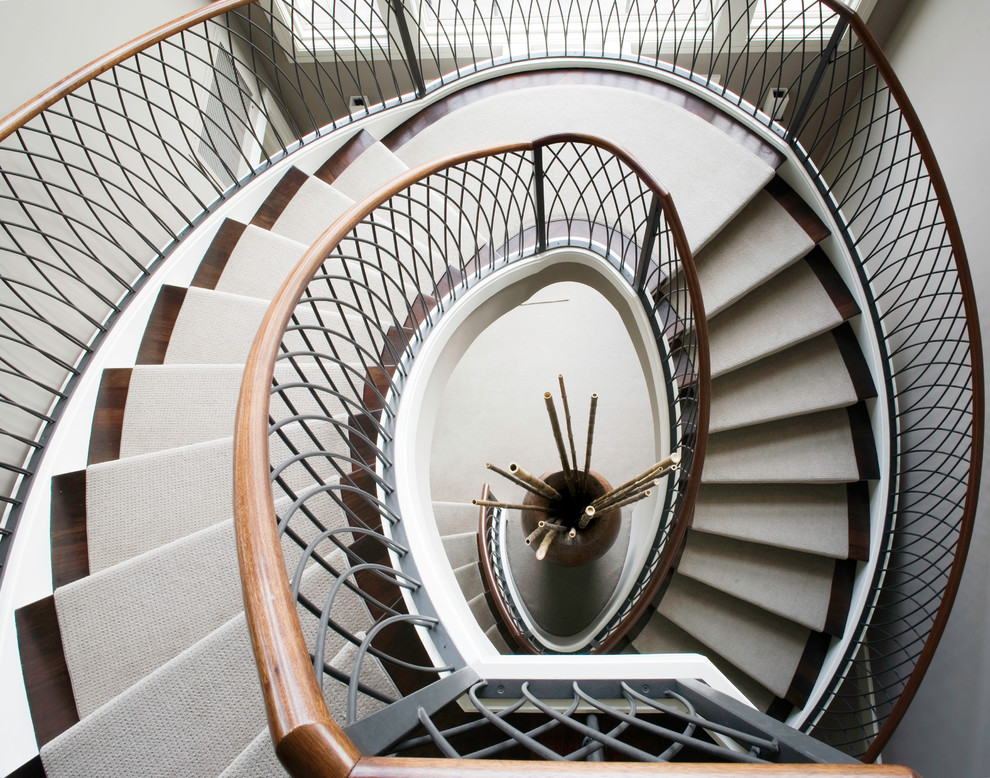 Cette image montre un grand escalier hélicoïdal design avec des marches en moquette et des contremarches en métal.