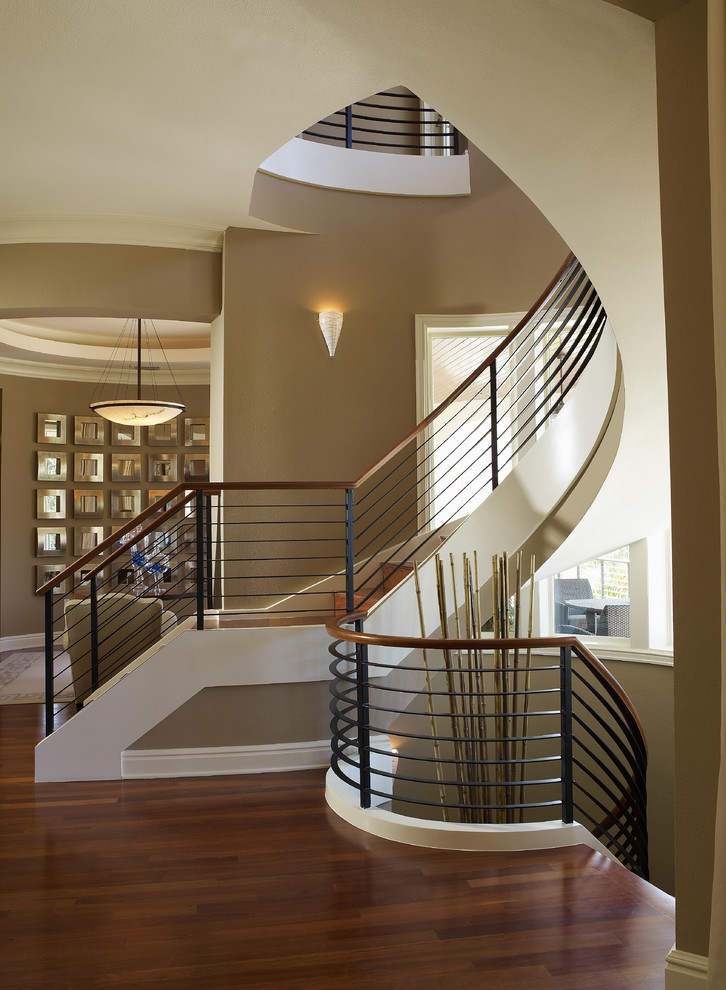 Imagen de escalera curva contemporánea de tamaño medio con escalones de madera, contrahuellas de madera y barandilla de metal
