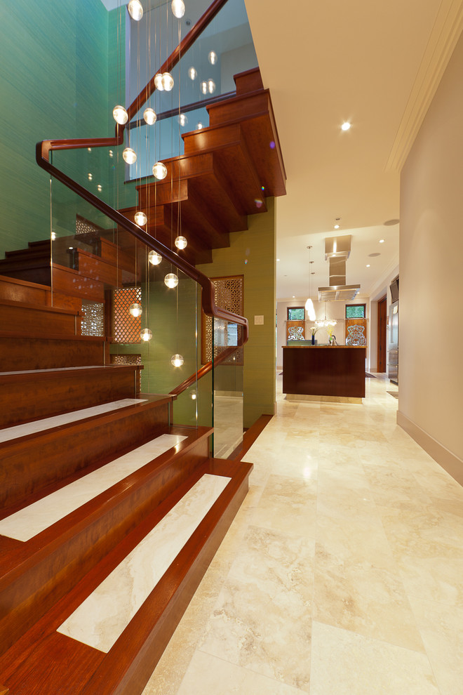 Diseño de escalera actual con barandilla de vidrio, escalones de travertino y contrahuellas de madera