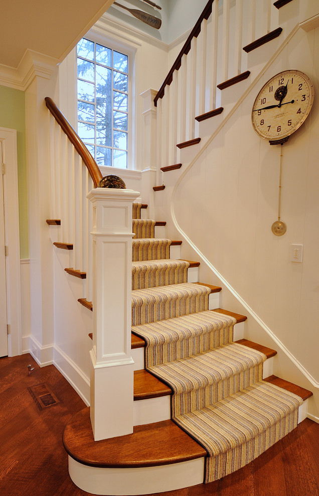 Diseño de escalera curva costera de tamaño medio con escalones de madera, contrahuellas de madera pintada y barandilla de madera