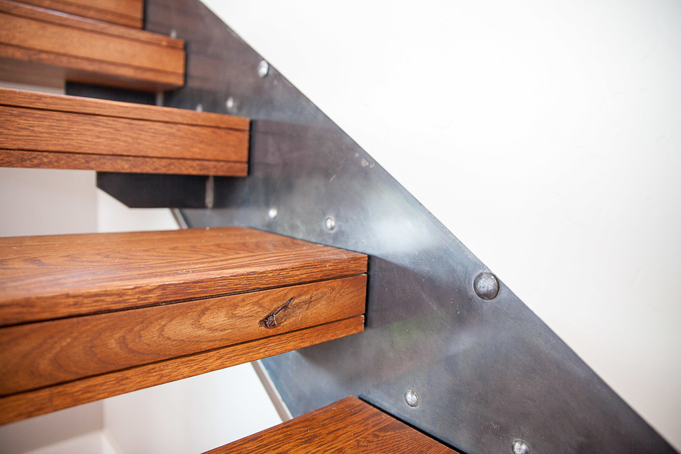 Modelo de escalera suspendida minimalista grande sin contrahuella con escalones de madera y barandilla de metal