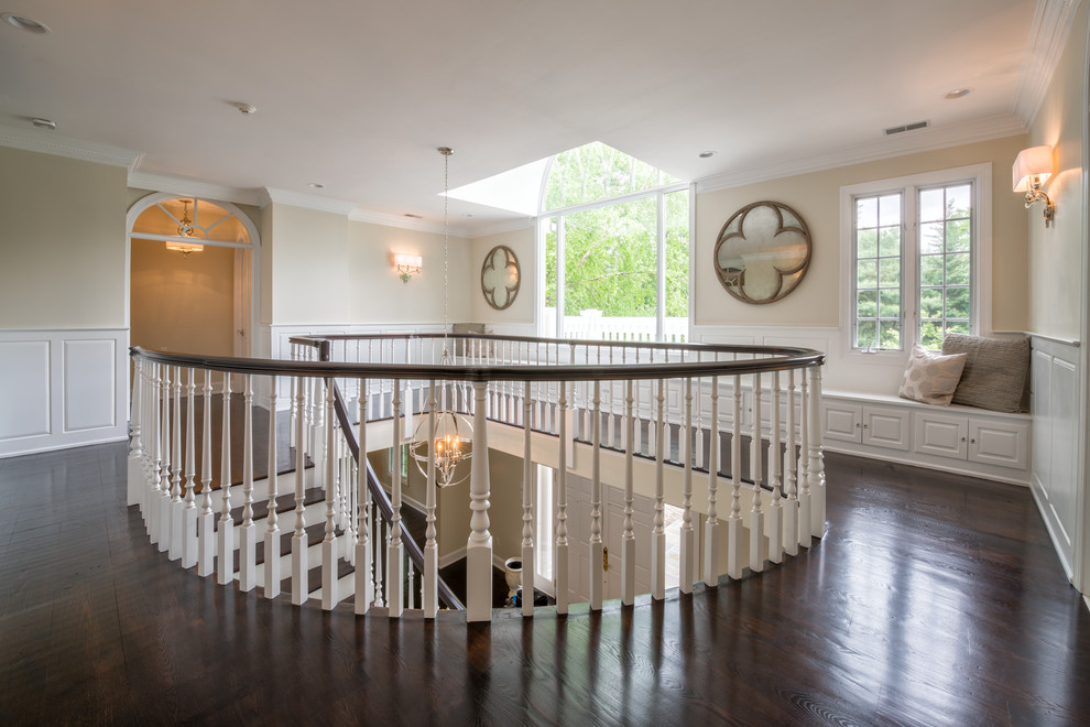 Aménagement d'un très grand escalier courbe classique avec des marches en bois, des contremarches en bois et un garde-corps en bois.