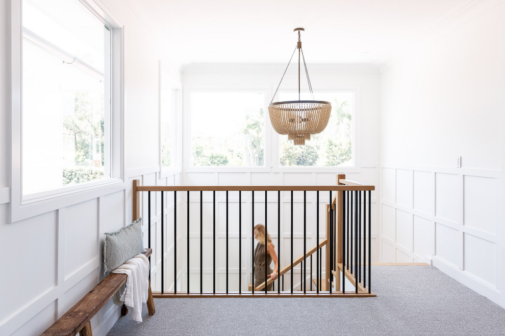 Aménagement d'un grand escalier peint bord de mer en U avec des marches en bois, un garde-corps en matériaux mixtes et boiseries.