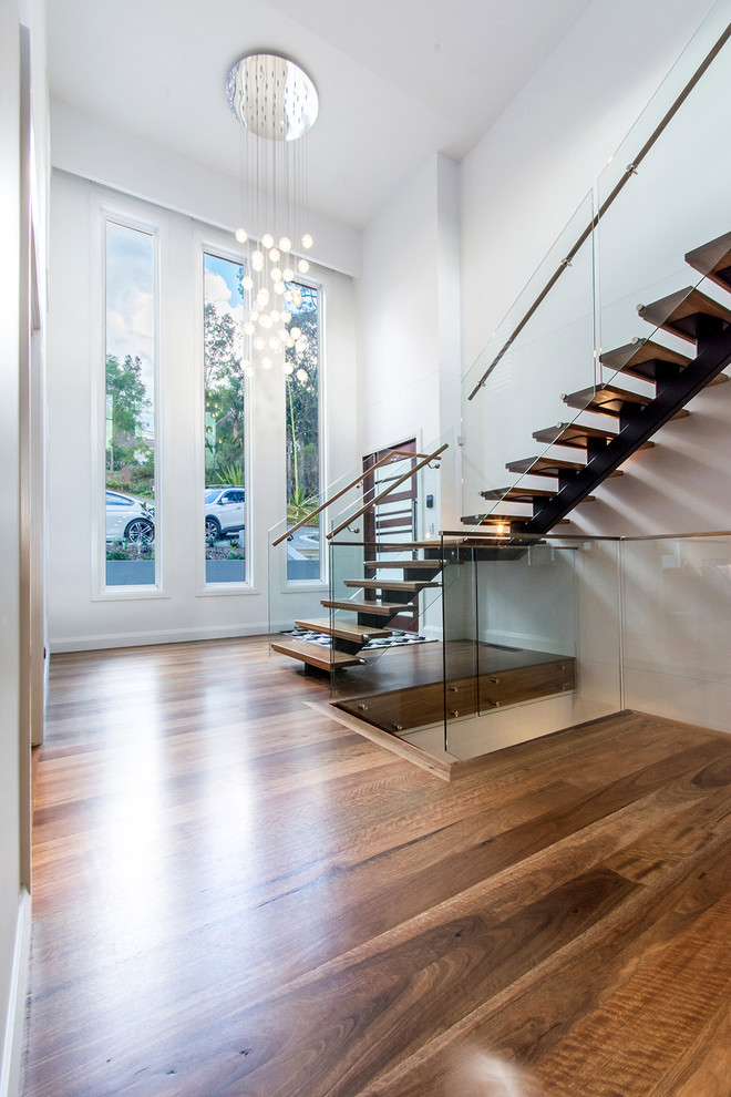 This is an example of a large traditional wood l-shaped glass railing staircase in Sydney with open risers.