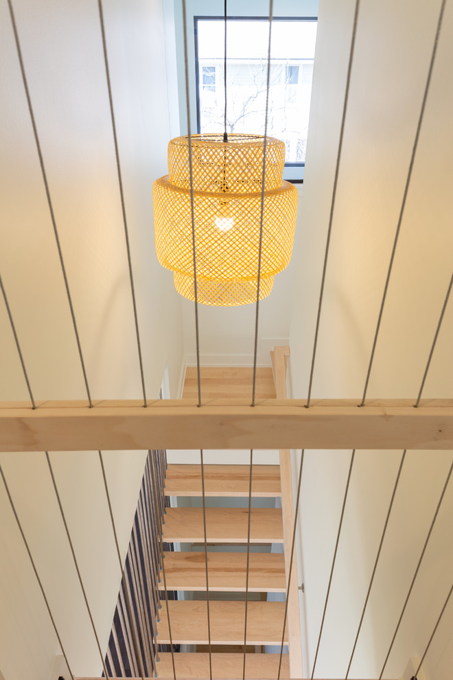 Imagen de escalera suspendida minimalista pequeña sin contrahuella con escalones de madera y barandilla de cable