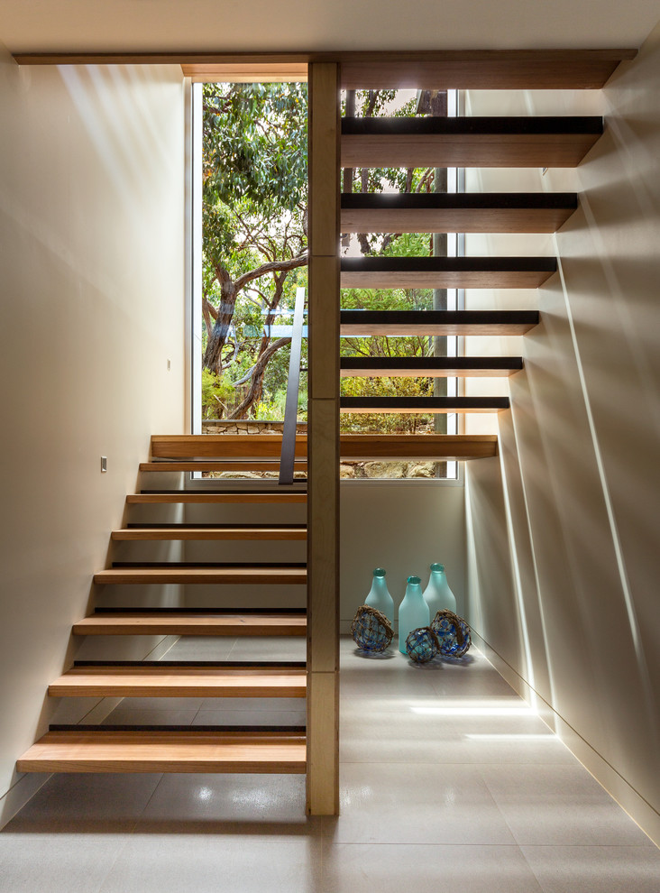 Idée de décoration pour un escalier design avec des marches en bois, des contremarches en bois et un garde-corps en métal.