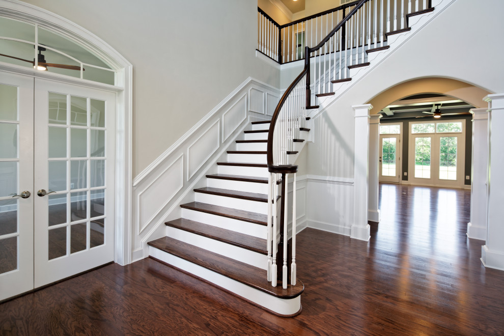На фото: угловая деревянная лестница среднего размера в классическом стиле с деревянными ступенями, деревянными перилами и панелями на стенах
