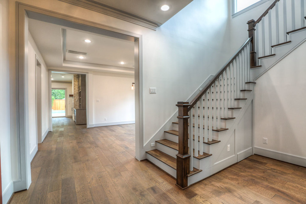 This is an example of a large classic wood u-shaped wood railing staircase in Houston with painted wood risers.