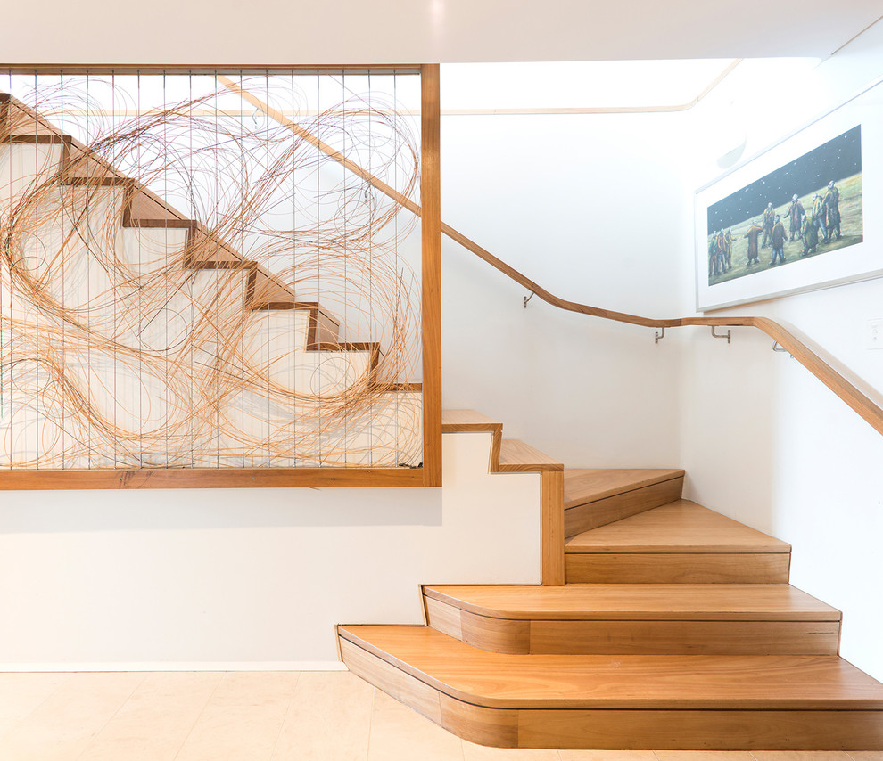 Idée de décoration pour un escalier courbe design avec des marches en bois, des contremarches en bois et un garde-corps en bois.