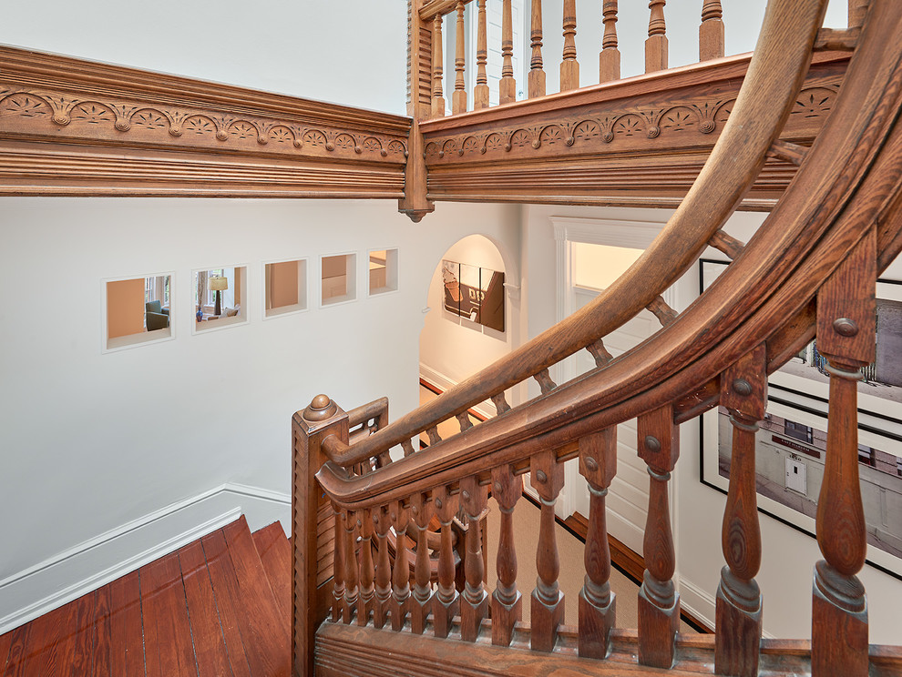 Modelo de escalera en U actual grande con escalones de madera, contrahuellas de madera y barandilla de madera