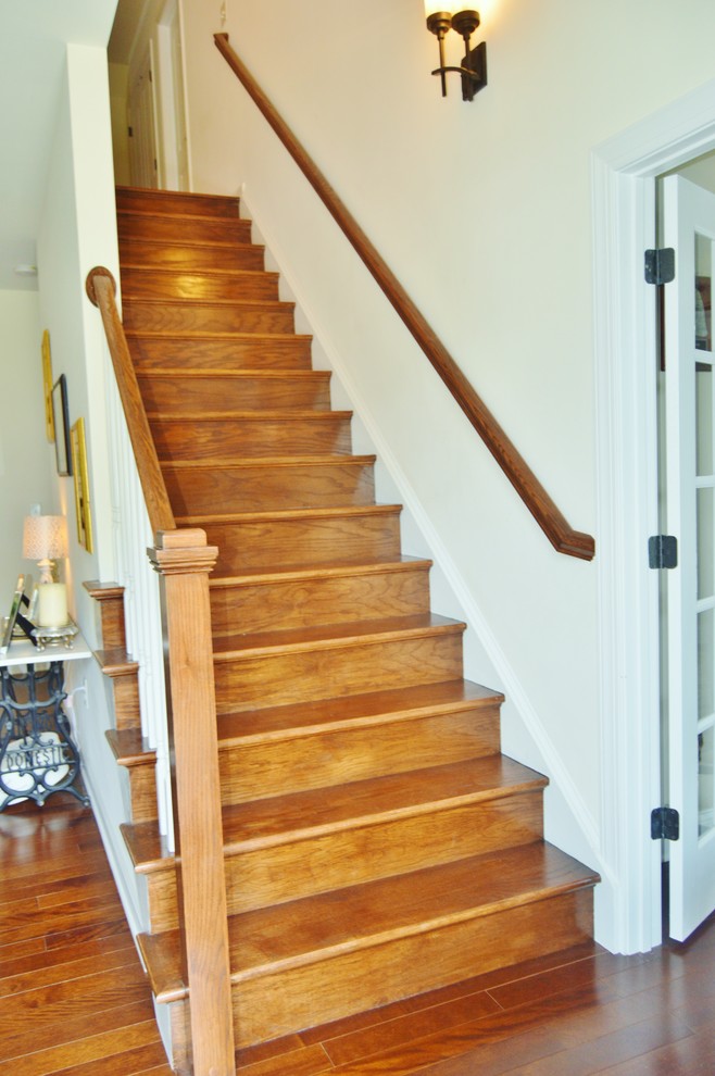 Foto de escalera recta de estilo americano de tamaño medio con escalones de madera, contrahuellas de madera y barandilla de madera