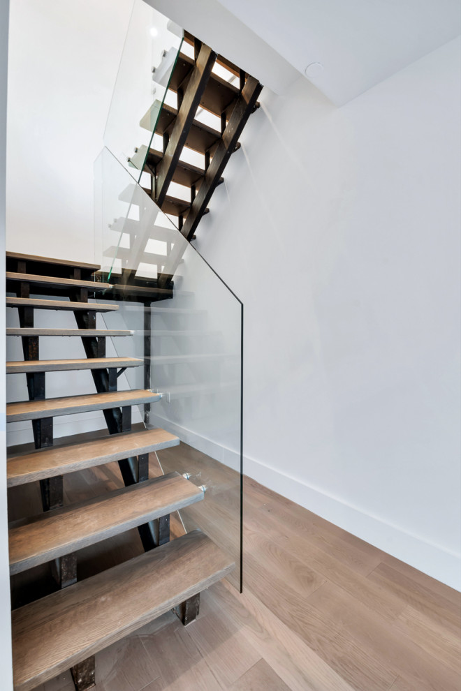 Modelo de escalera suspendida minimalista grande con escalones de metal, contrahuellas de madera y barandilla de vidrio