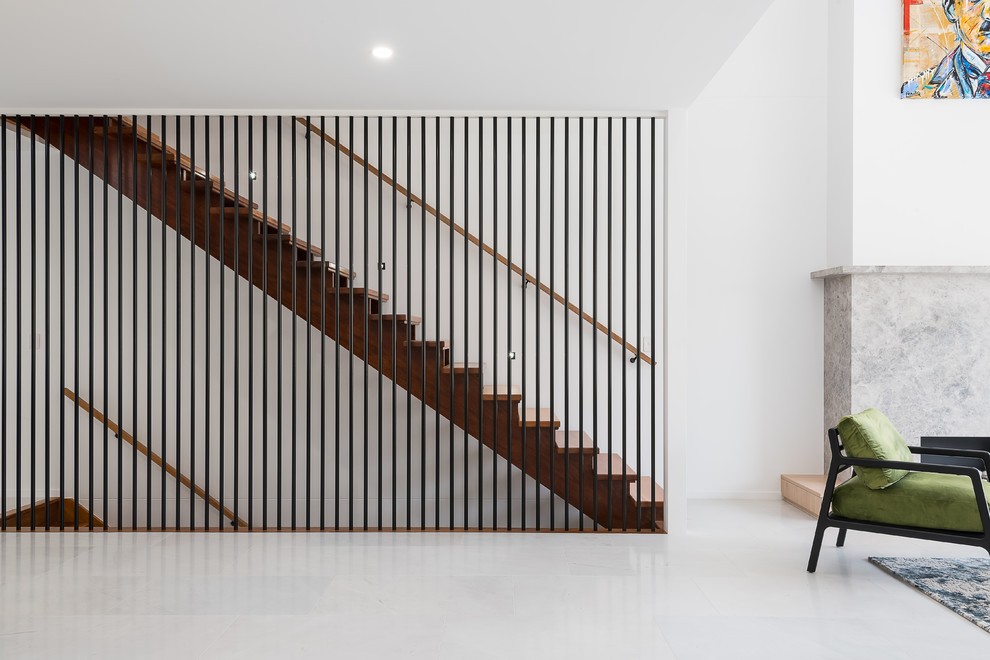 Réalisation d'un grand escalier droit design avec des marches en bois, des contremarches en bois et un garde-corps en métal.