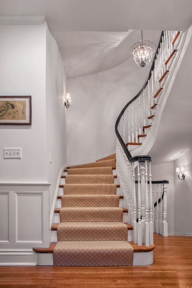 Cette photo montre un grand escalier peint courbe chic avec des marches en bois.