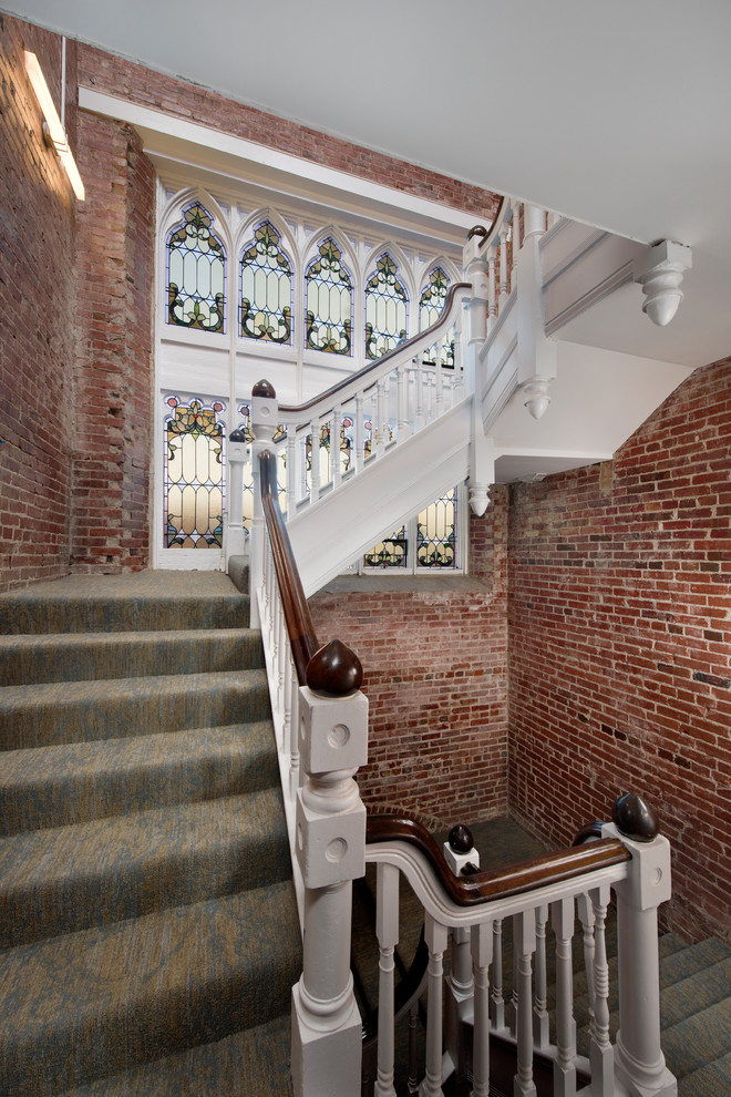 На фото: п-образная лестница в викторианском стиле с ступенями с ковровым покрытием, ковровыми подступенками и деревянными перилами