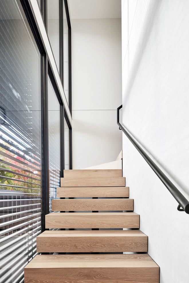 メルボルンにあるラグジュアリーなコンテンポラリースタイルのおしゃれなかね折れ階段 (木の蹴込み板、金属の手すり) の写真