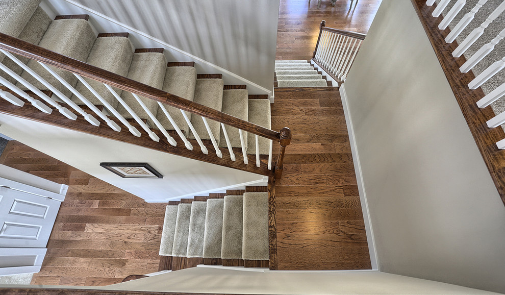 Imagen de escalera en U de estilo americano grande con escalones de madera y contrahuellas enmoquetadas