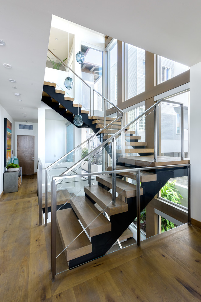 Foto de escalera en U contemporánea sin contrahuella con escalones de madera y barandilla de vidrio