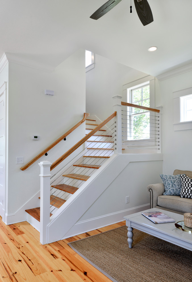 Foto de escalera en L de estilo de casa de campo de tamaño medio con escalones de madera, contrahuellas de madera pintada y barandilla de cable