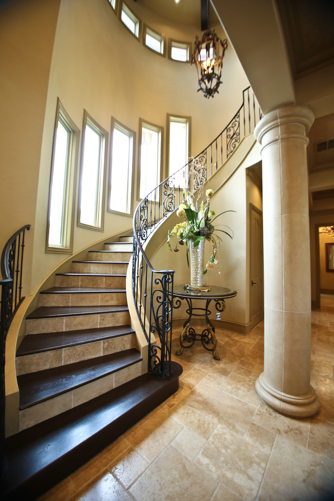 Large mediterranean wood curved staircase in Houston with tiled risers.