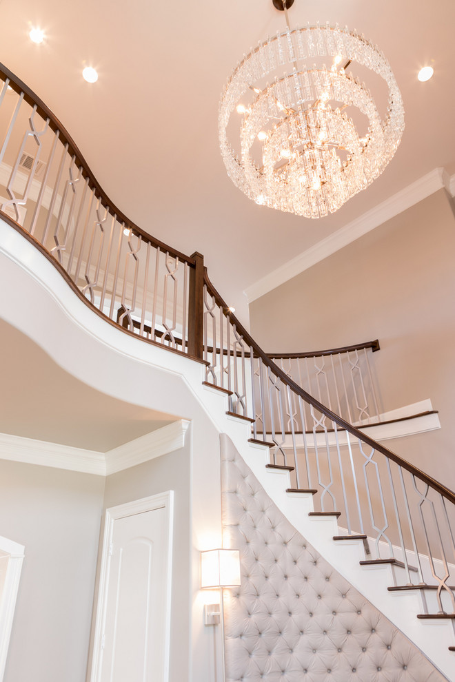 Large traditional wood curved wood railing staircase in Houston with painted wood risers.