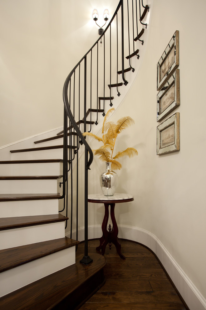 Imagen de escalera curva tradicional con escalones de madera y barandilla de metal