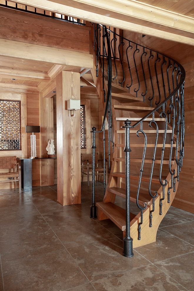 Réalisation d'un grand escalier courbe bohème avec des marches en bois et un garde-corps en métal.