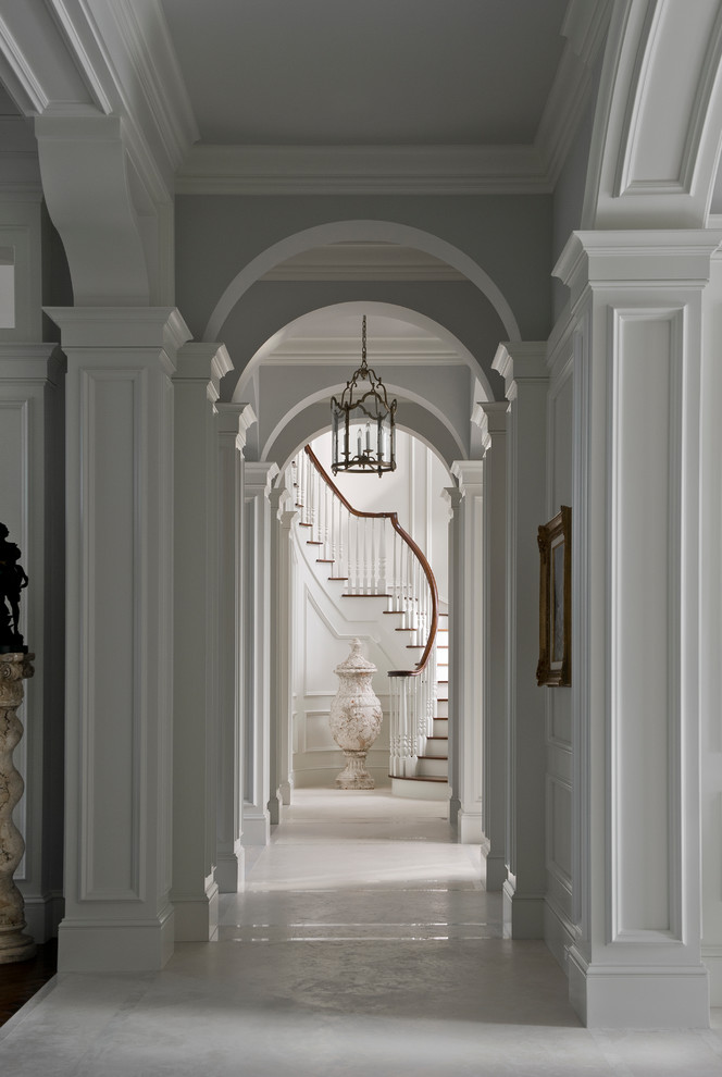 На фото: большая изогнутая лестница в классическом стиле с деревянными ступенями и крашенными деревянными подступенками с
