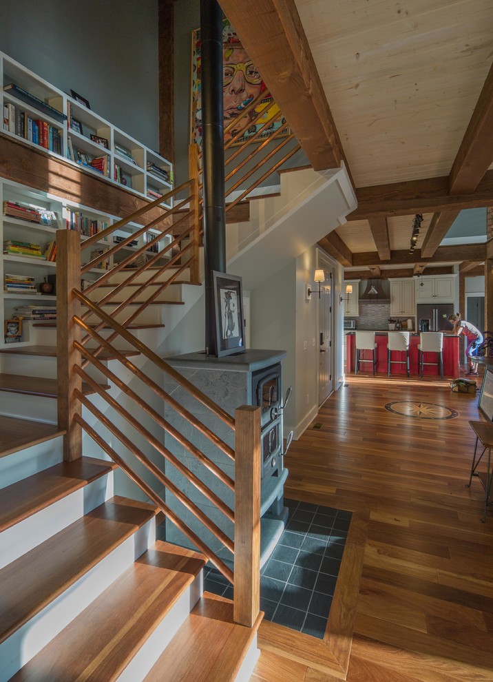 Imagen de escalera en L rústica grande con escalones de madera, contrahuellas de madera pintada y barandilla de madera